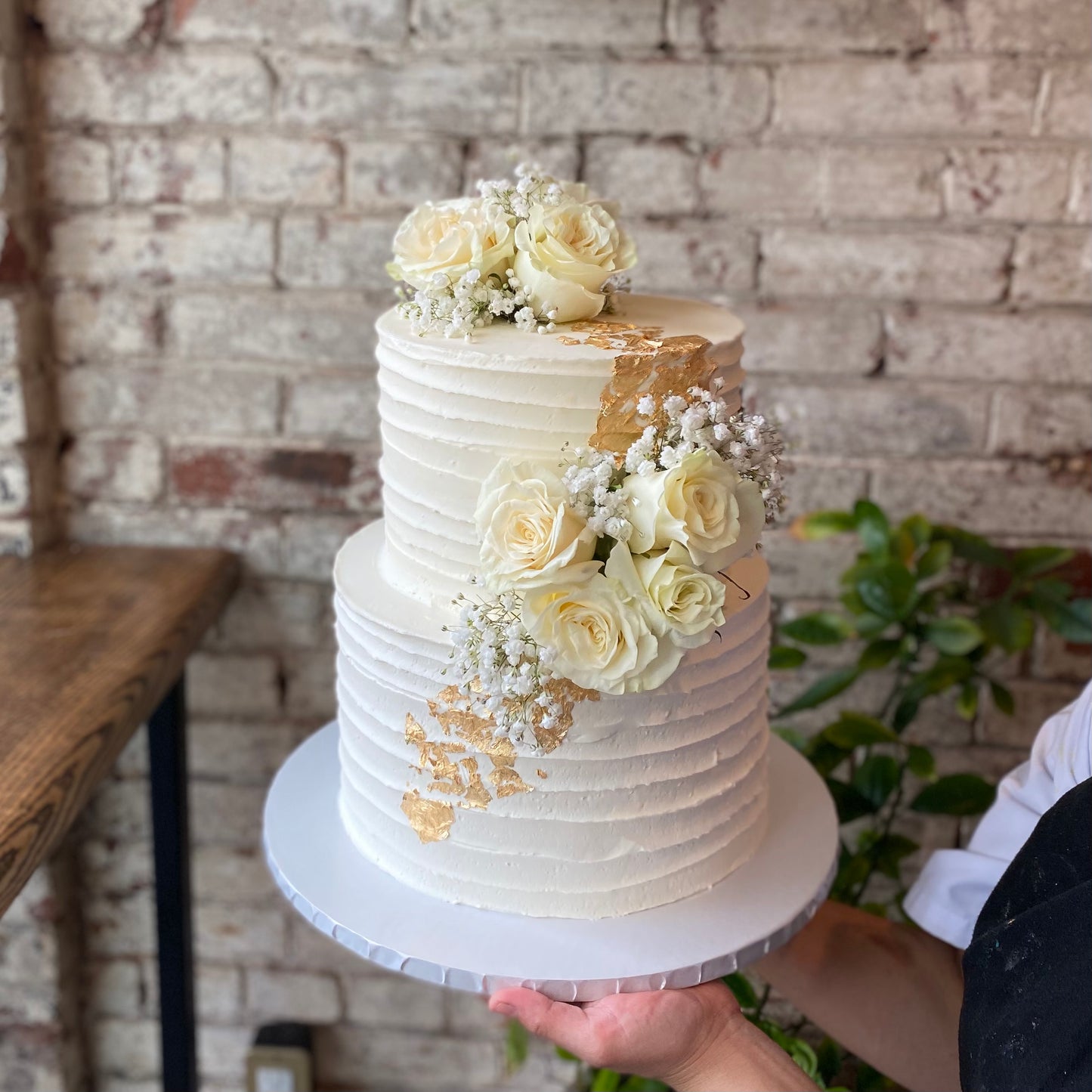 Two-tiered white wedding cake with fresh flowers
